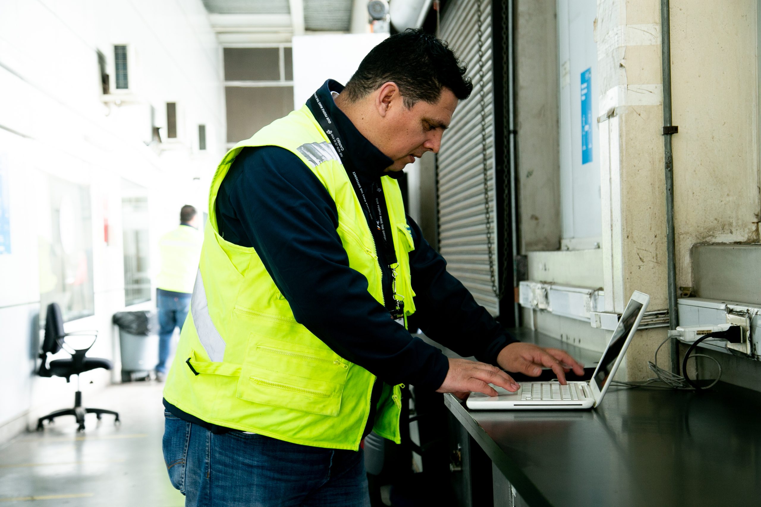 Trabajador logístico revisando información en un computador portátil dentro de una bodega